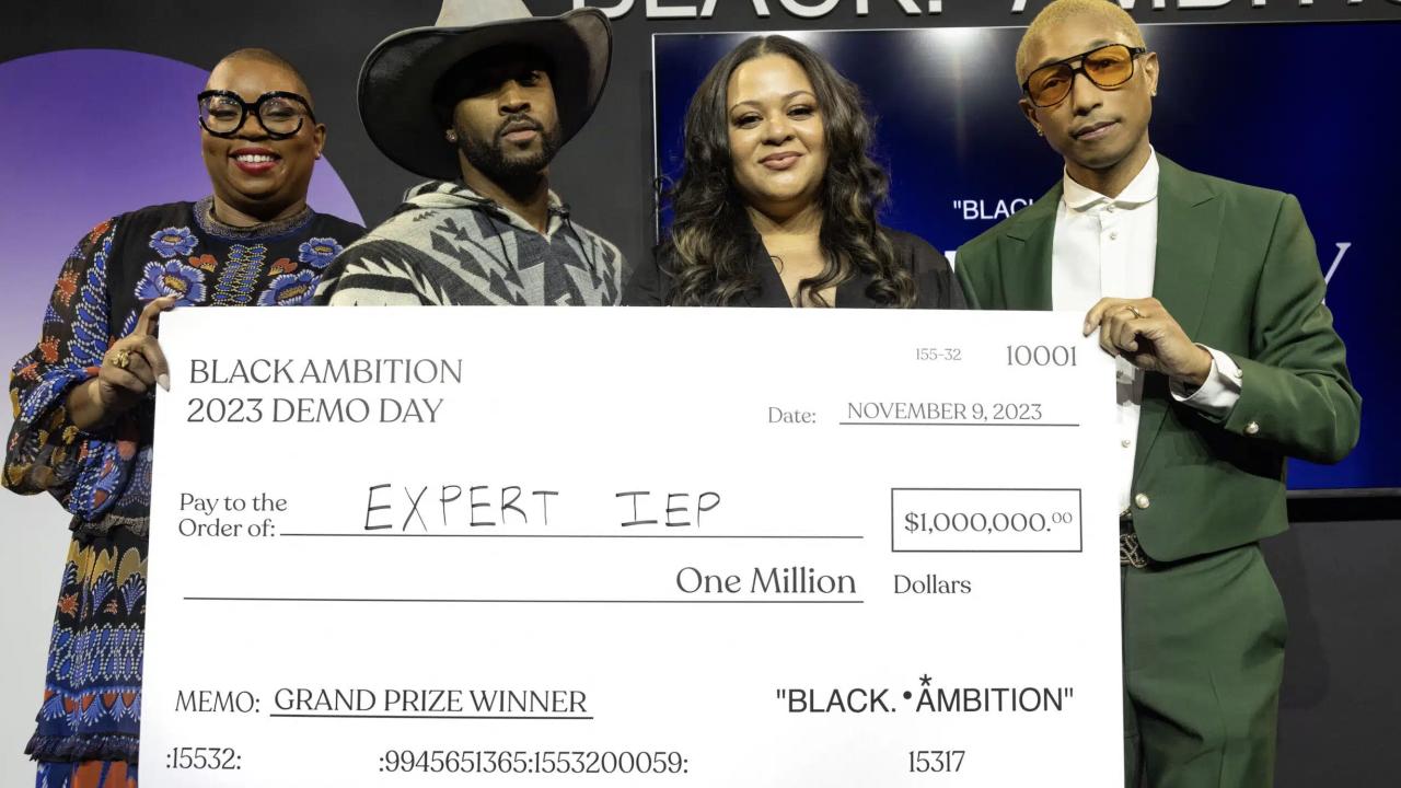 Antoinette Banks poses with her award check and Black Ambition CEO Felecia Hatcher, Leonard Creer, and Pharrell Williams