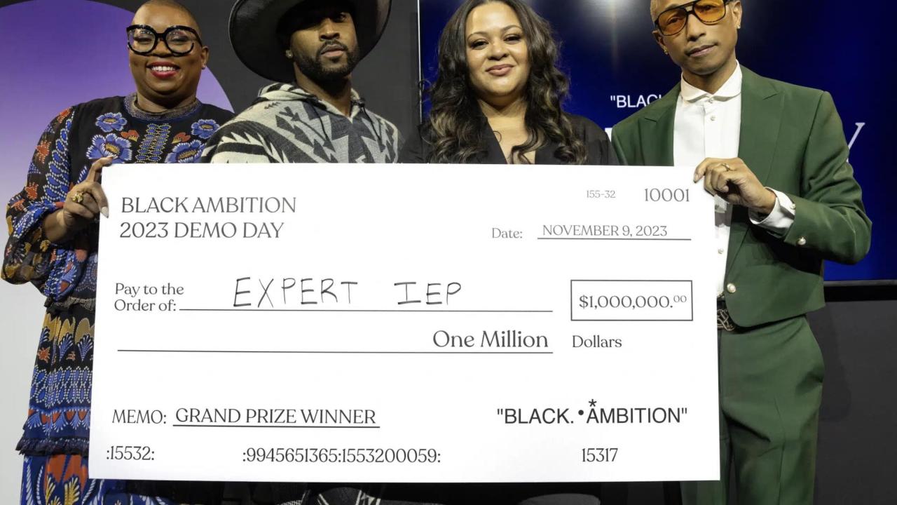 Antoinette Banks poses with her award check and Black Ambition CEO Felecia Hatcher, Leonard Creer, and Pharrell Williams
