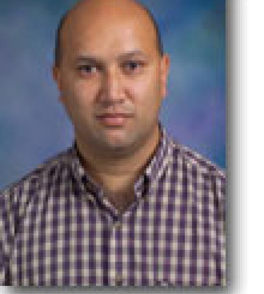 A bald man wearing a burgundy checkered shirt
